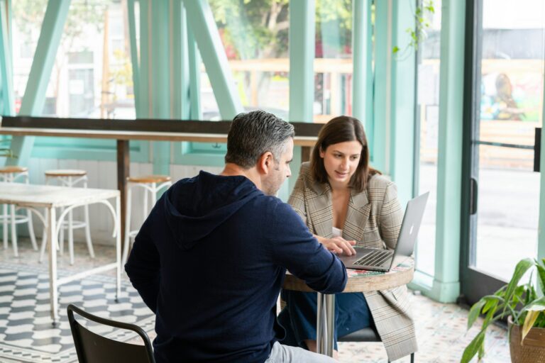 Un homme et une femme attablés au café et regardant un ordinateur